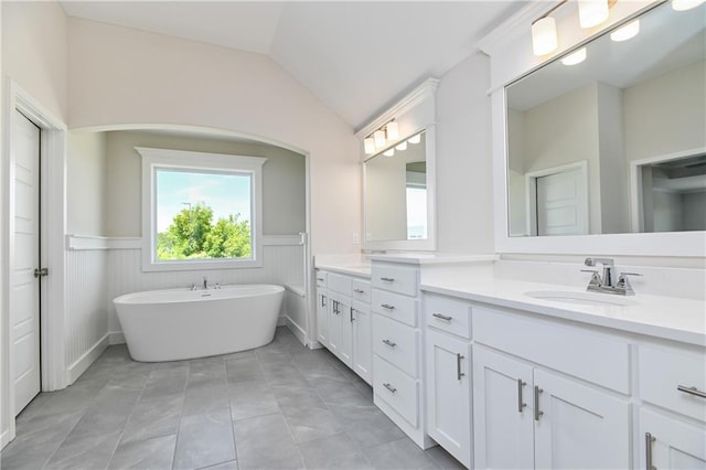 6108 Lewis Dr, Shawnee, KS 66226 - full bath with double vanity, a wainscoted wall, vaulted ceiling, and a soaking tub