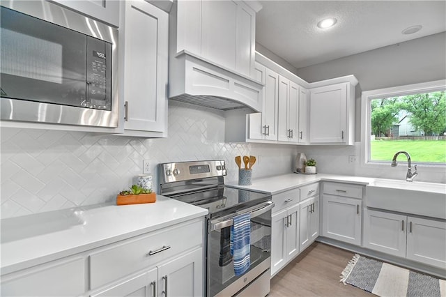 6118 Lewis Dr, Shawnee, KS 66226 - kitchen with stainless steel appliances, light countertops, decorative backsplash, light wood-type flooring, and white cabinetry