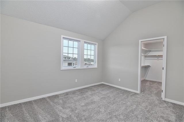 6118 Lewis Dr, Shawnee, KS 66226 - unfurnished bedroom featuring carpet floors, a spacious closet, vaulted ceiling, a closet, and a textured ceiling