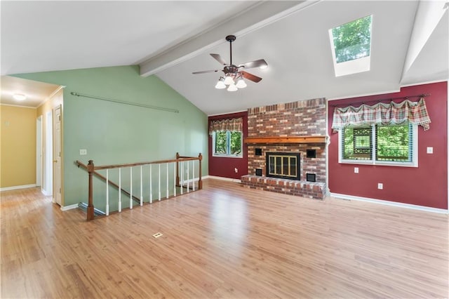 32204 Apple Hill Dr, Paola, KS 66071 - unfurnished living room featuring wood finished floors, a ceiling fan, a skylight, and a brick fireplace