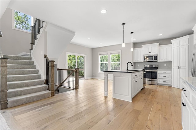 16779 S Durango St, Olathe, KS 66062 - kitchen with appliances with stainless steel finishes, a breakfast bar, light wood finished floors, recessed lighting, and white cabinetry
