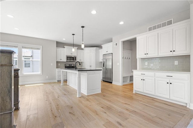 16779 S Durango St, Olathe, KS 66062 - kitchen with appliances with stainless steel finishes, tasteful backsplash, light wood finished floors, white cabinets, and pendant lighting