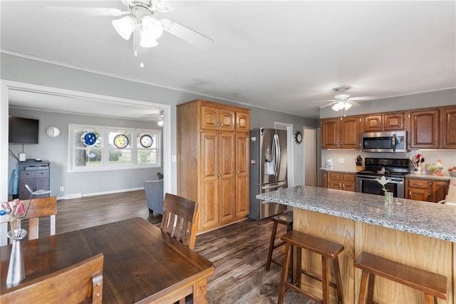 24245 K 68 Hwy, Paola, KS 66071 - kitchen featuring stainless steel appliances, a ceiling fan, a peninsula, dark wood-style floors, and a breakfast bar