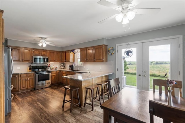 24245 K 68 Hwy, Paola, KS 66071 - kitchen featuring appliances with stainless steel finishes, ceiling fan, a peninsula, dark wood-style floors, and plenty of natural light