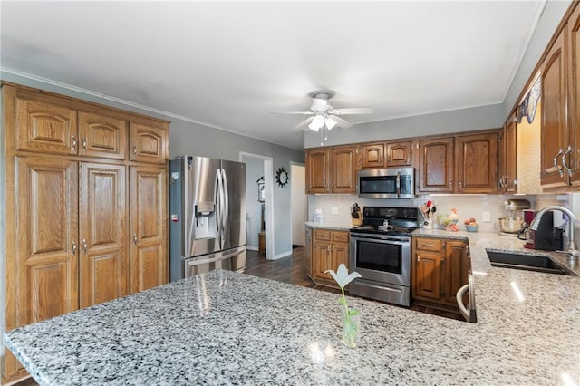 24245 K 68 Hwy, Paola, KS 66071 - kitchen featuring stainless steel appliances, ceiling fan, light stone counters, brown cabinets, and a peninsula