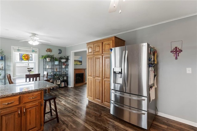 24245 K 68 Hwy, Paola, KS 66071 - kitchen featuring stainless steel fridge with ice dispenser, a breakfast bar, dark wood-style flooring, ceiling fan, and light stone countertops
