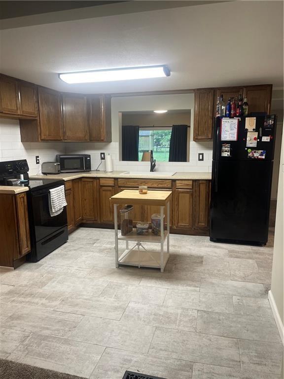 400 N Institute St, Richmond, MO 64085 - kitchen with black appliances, light countertops, and decorative backsplash