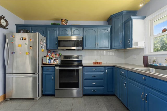 820 S Main St, Lansing, KS 66043 - kitchen featuring stainless steel appliances, blue cabinetry, and backsplash
