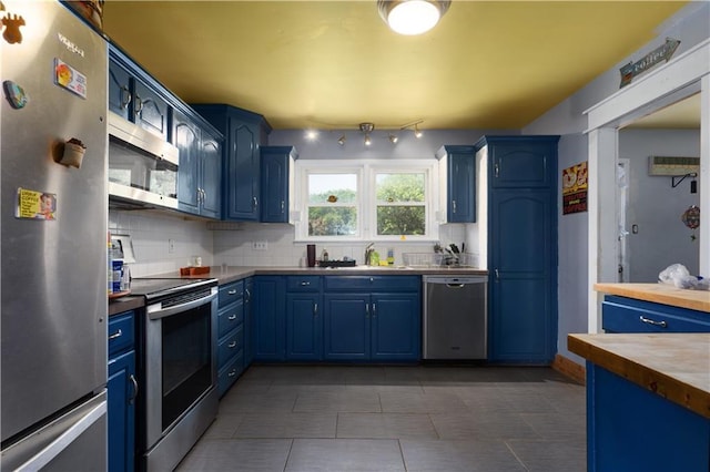 820 S Main St, Lansing, KS 66043 - kitchen with appliances with stainless steel finishes, blue cabinetry, and backsplash