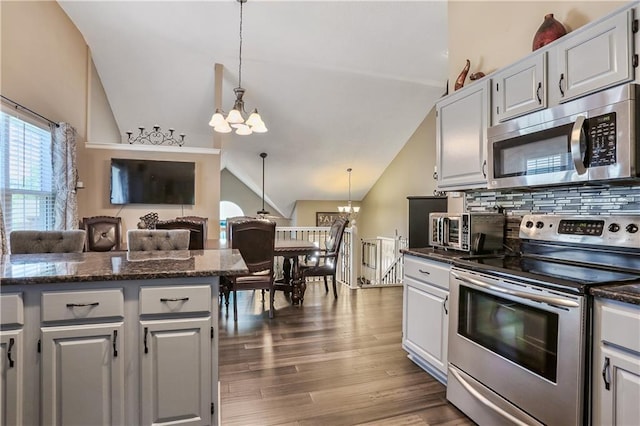 1641 N Hunter Dr, Olathe, KS 66061 - kitchen featuring appliances with stainless steel finishes, a chandelier, vaulted ceiling, tasteful backsplash, and dark wood-type flooring