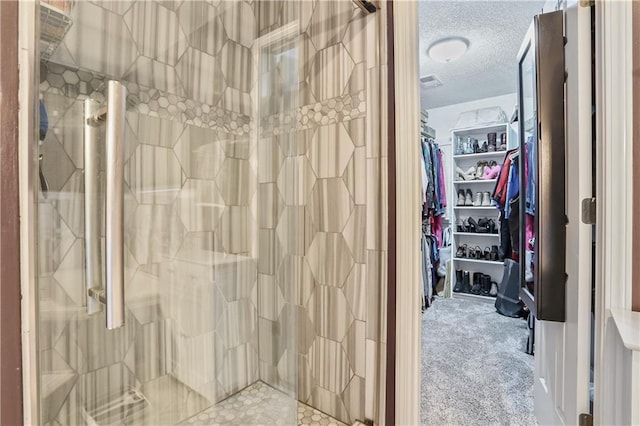 1641 N Hunter Dr, Olathe, KS 66061 - bathroom featuring a textured ceiling, a walk in closet, and a tile shower