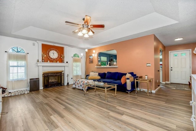 118 SE 215th Rd, Warrensburg, MO 64093 - living room featuring a raised ceiling, a ceiling fan, wood finished floors, a fireplace, and a textured ceiling
