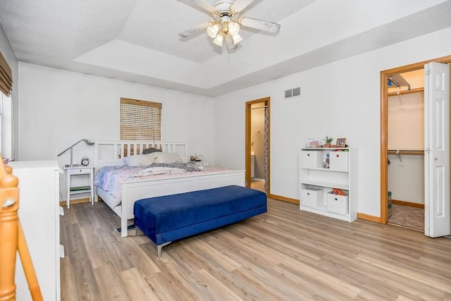 118 SE 215th Rd, Warrensburg, MO 64093 - bedroom with a tray ceiling, light wood finished floors, a walk in closet, a closet, and ceiling fan