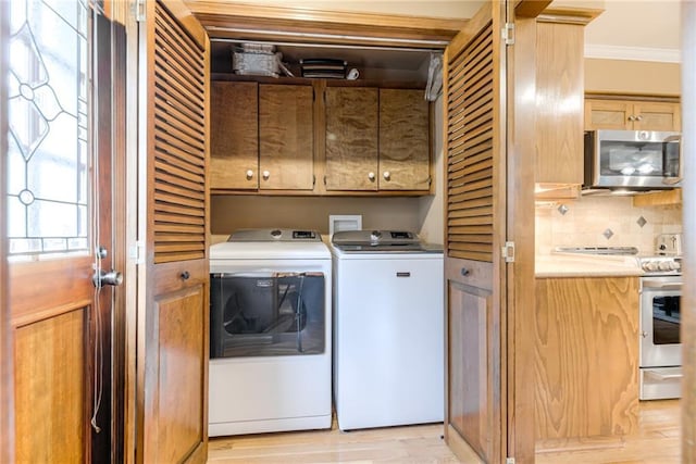 8404 Rosehill Rd, Lenexa, KS 66215 - laundry room with separate washer and dryer, cabinet space, ornamental molding, and light wood-style flooring
