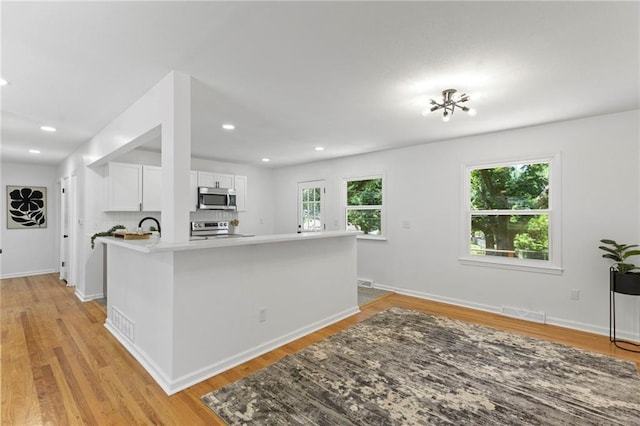 8918 Switzer St, Overland Park, KS 66214 - kitchen with appliances with stainless steel finishes, white cabinetry, light wood-type flooring, light countertops, and recessed lighting