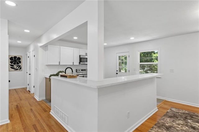 8918 Switzer St, Overland Park, KS 66214 - kitchen with appliances with stainless steel finishes, white cabinets, light wood finished floors, tasteful backsplash, and recessed lighting