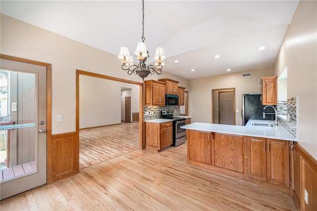 19208 E Lynchburg Pl, Independence, MO 64058 - kitchen featuring appliances with stainless steel finishes, light wood-type flooring, lofted ceiling, a chandelier, and a peninsula