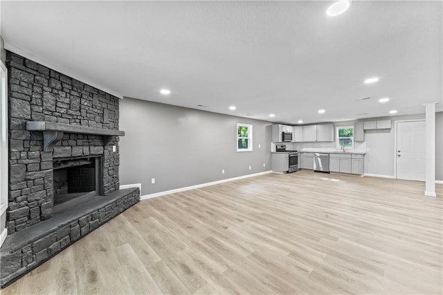 5513 Hardy Ave, Raytown, MO 64133 - unfurnished living room featuring recessed lighting, a stone fireplace, and light wood-style floors