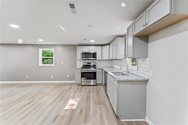 5513 Hardy Ave, Raytown, MO 64133 - kitchen featuring stainless steel appliances, backsplash, light wood-style flooring, light stone counters, and recessed lighting