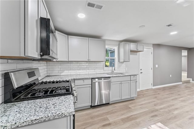 5513 Hardy Ave, Raytown, MO 64133 - kitchen featuring appliances with stainless steel finishes, backsplash, light wood-type flooring, light stone countertops, and recessed lighting