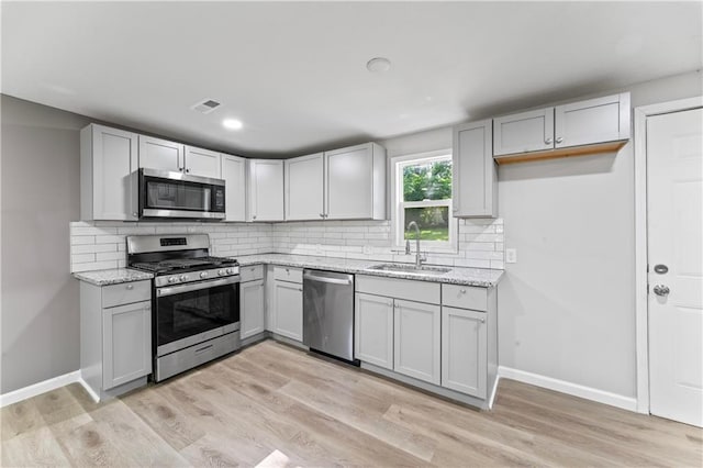 5513 Hardy Ave, Raytown, MO 64133 - kitchen featuring stainless steel appliances, light stone counters, backsplash, light wood finished floors, and recessed lighting