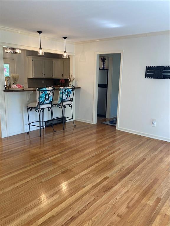 7909 Appleton Ave, Raytown, MO 64138 - kitchen with freestanding refrigerator, dark countertops, a breakfast bar area, light wood-type flooring, and pendant lighting