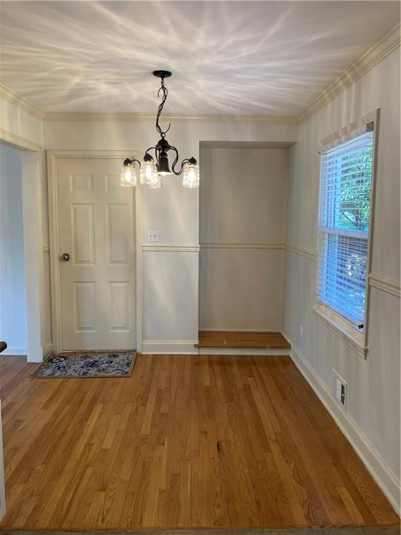 7909 Appleton Ave, Raytown, MO 64138 - unfurnished dining area with a chandelier, ornamental molding, and wood finished floors