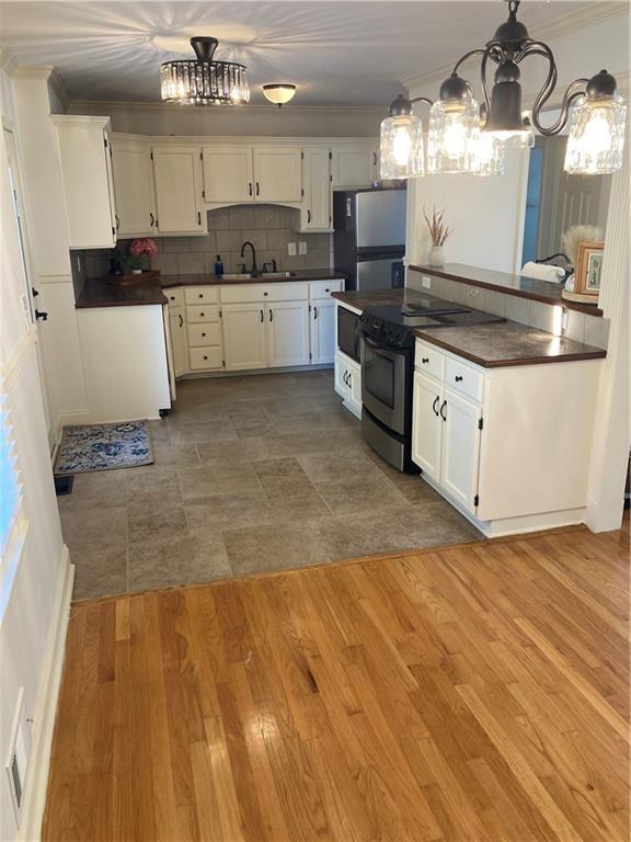 7909 Appleton Ave, Raytown, MO 64138 - kitchen featuring a chandelier, stainless steel appliances, dark countertops, and ornamental molding