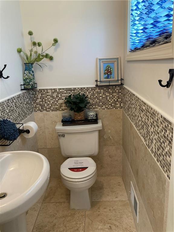 7909 Appleton Ave, Raytown, MO 64138 - half bathroom featuring tile walls, wainscoting, and tile patterned floors