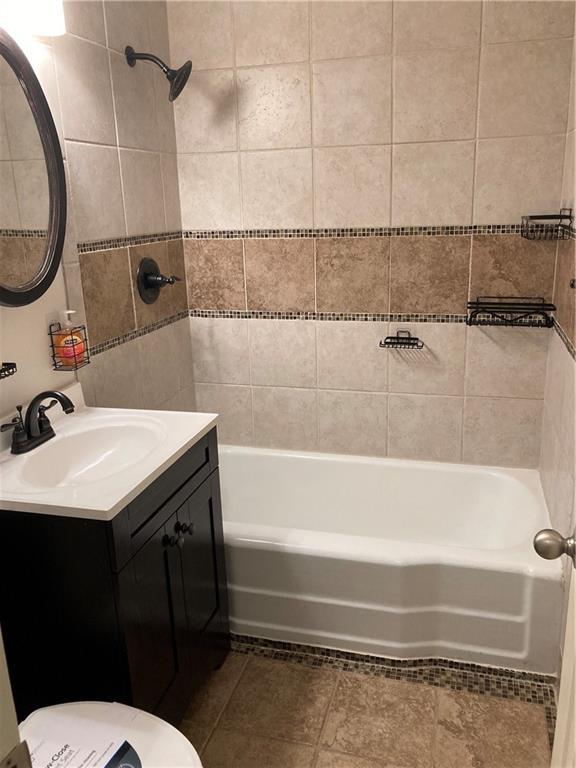 7909 Appleton Ave, Raytown, MO 64138 - bathroom with vanity, shower / washtub combination, tile patterned floors, and tile walls