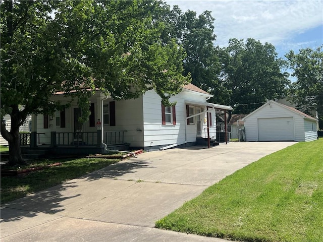 409 S Buckeye St, Iola, KS 66749 - view of front facade featuring a porch, an outdoor structure, a garage, a front lawn, and concrete driveway
