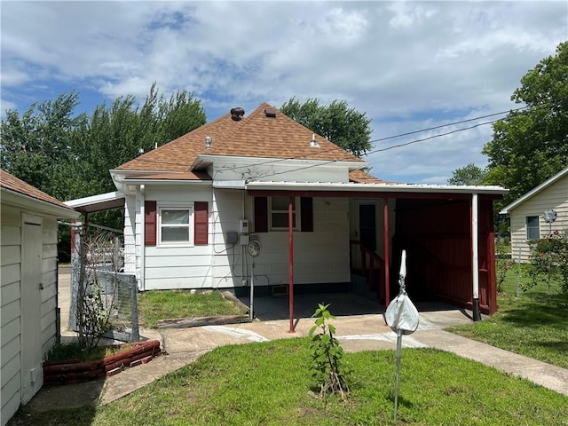 409 S Buckeye St, Iola, KS 66749 - back of property featuring a lawn, a shingled roof, and a carport
