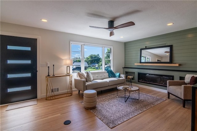 2031 N 75th St, Kansas City, KS 66109 - living room with ceiling fan, wood finished floors, a glass covered fireplace, recessed lighting, and wood walls