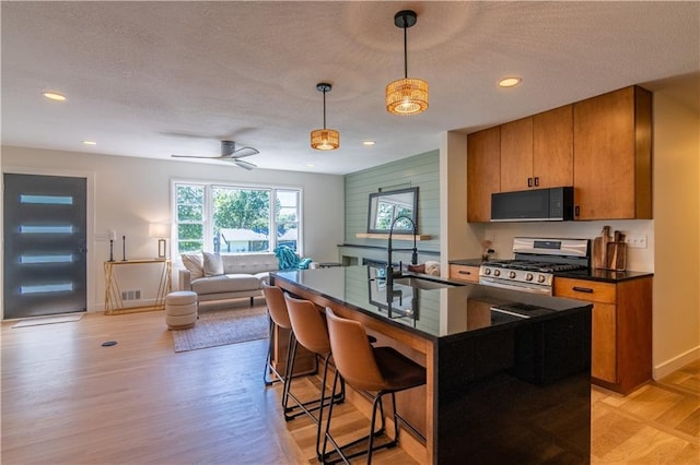2031 N 75th St, Kansas City, KS 66109 - kitchen with stainless steel gas range oven, black microwave, dark countertops, a textured ceiling, and open floor plan