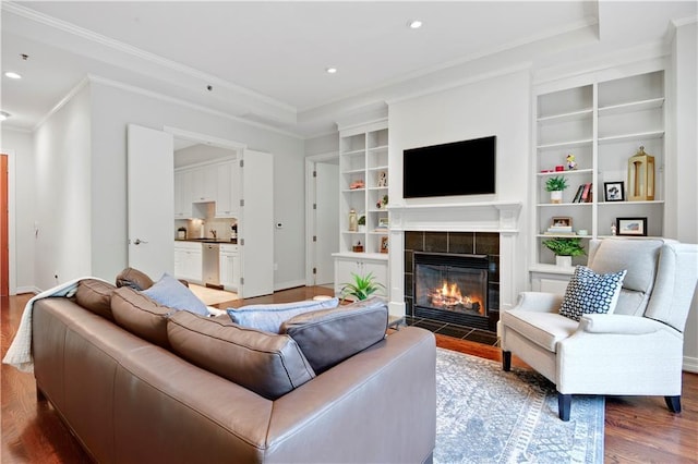 4900 Central St Unit 104, Kansas City, MO 64112 - living area with wood finished floors, a tiled fireplace, ornamental molding, recessed lighting, and built in shelves