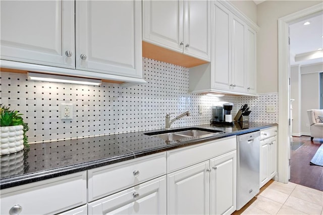 4900 Central St Unit 104, Kansas City, MO 64112 - kitchen featuring stainless steel dishwasher, white cabinetry, backsplash, dark stone countertops, and light tile patterned floors