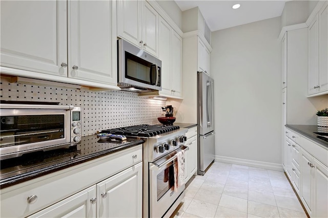 4900 Central St Unit 104, Kansas City, MO 64112 - kitchen featuring stainless steel appliances, dark countertops, tasteful backsplash, white cabinetry, and recessed lighting
