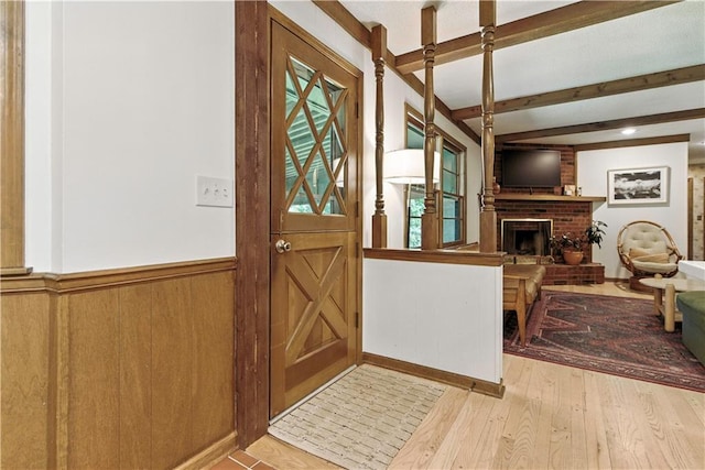 7100 Antioch Rd, Merriam, KS 66204 - foyer entrance featuring beam ceiling, a brick fireplace, wood finished floors, a wainscoted wall, and wooden walls