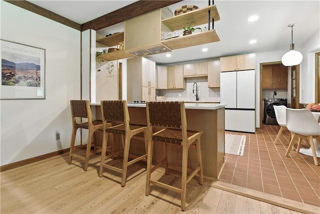 7100 Antioch Rd, Merriam, KS 66204 - kitchen with freestanding refrigerator, separate washer and dryer, open shelves, light countertops, and tasteful backsplash