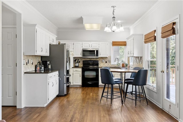 14162 W 150th Ct, Olathe, KS 66062 - kitchen featuring appliances with stainless steel finishes, dark countertops, a chandelier, backsplash, and ornamental molding