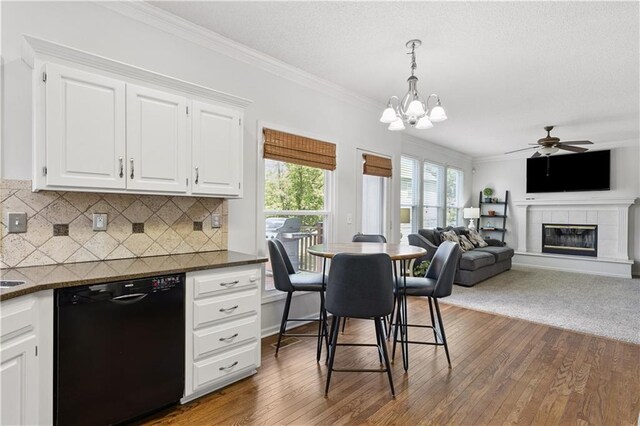 14162 W 150th Ct, Olathe, KS 66062 - dining space featuring ornamental molding, ceiling fan, dark wood-style flooring, a chandelier, and a tiled fireplace