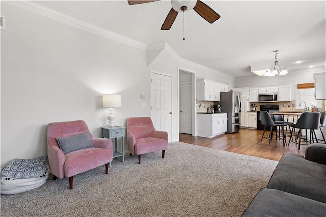 14162 W 150th Ct, Olathe, KS 66062 - living area with a chandelier, a ceiling fan, crown molding, and dark colored carpet