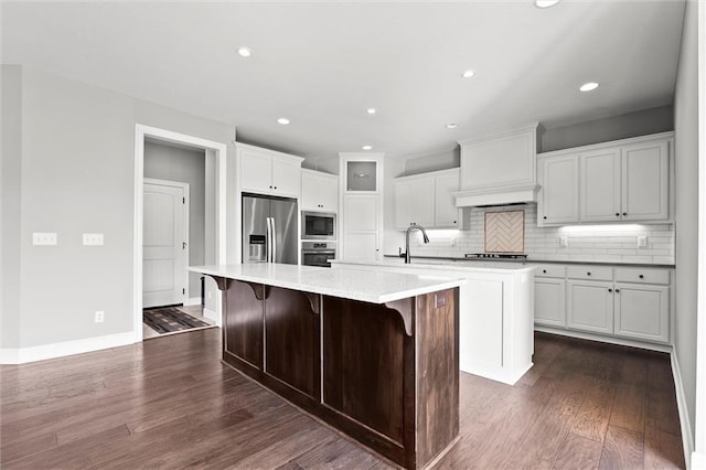 704 SW Admiral Byrd Dr, Lees Summit, MO 64082 - kitchen with stainless steel appliances, a large island, premium range hood, decorative backsplash, and dark wood finished floors