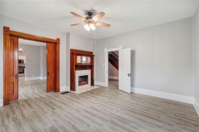 306 W 4th St, Cameron, MO 64429 - unfurnished living room featuring light wood-style flooring, a ceiling fan, and a tiled fireplace
