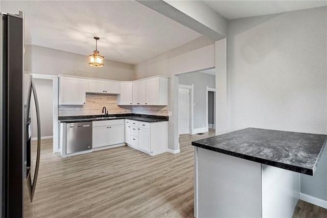 306 W 4th St, Cameron, MO 64429 - kitchen featuring stainless steel appliances, light wood-style floors, tasteful backsplash, white cabinetry, and dark countertops