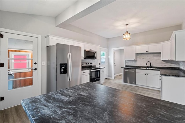 306 W 4th St, Cameron, MO 64429 - kitchen with appliances with stainless steel finishes, tasteful backsplash, wood finished floors, and white cabinets