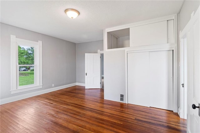 306 W 4th St, Cameron, MO 64429 - unfurnished bedroom featuring wood finished floors, a closet, and a textured ceiling