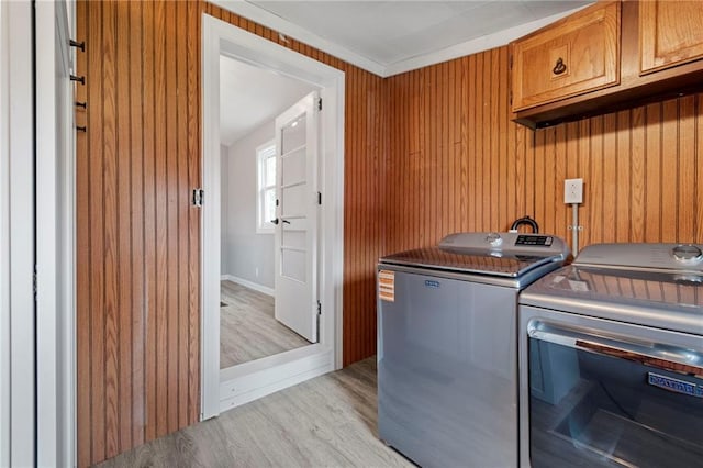306 W 4th St, Cameron, MO 64429 - laundry room featuring light wood-type flooring, washing machine and clothes dryer, cabinet space, and wooden walls