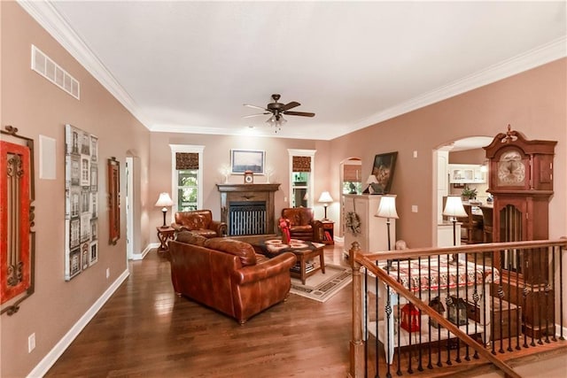 1310 Norfolk Dr, Harrisonville, MO 64701 - living room with a fireplace, a ceiling fan, dark wood-style flooring, crown molding, and arched walkways