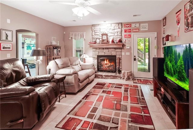 1310 Norfolk Dr, Harrisonville, MO 64701 - living room featuring light tile patterned floors, healthy amount of natural light, a ceiling fan, and a stone fireplace
